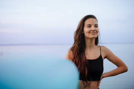 Young beautiful sportive girl with paddleboard on the lake at sunriseの写真素材