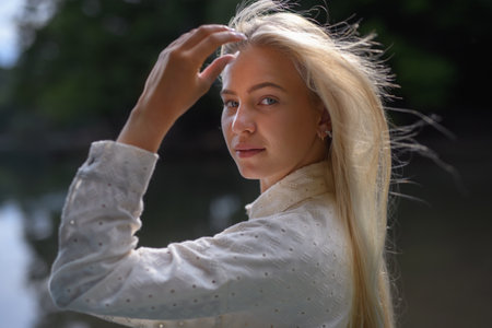 Portrait of beautiful blond young woman looking at camera and smiling outdoor in nature.の写真素材