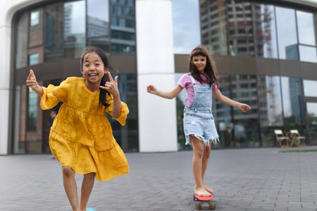 Happy children enjoying skateboard ride and going down the hill, looking at camera.の写真素材