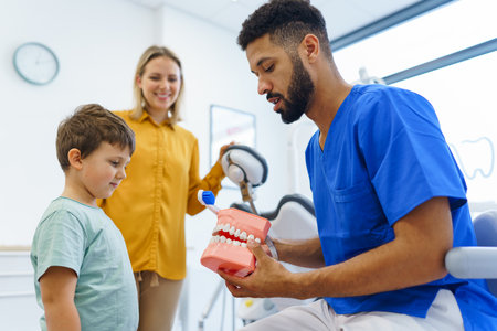 Young multiracial dentist showing little boy how to clean teeth, concept of children oral hygiene,prevention and dental health.の写真素材