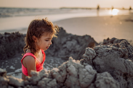 Little girl playing on the beach, digging hole in sand.の写真素材