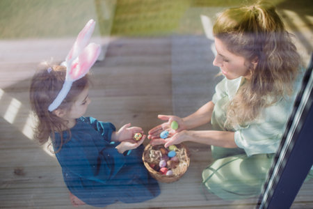 Little girl holding basket and showing her mother easter eggs which she found.の写真素材