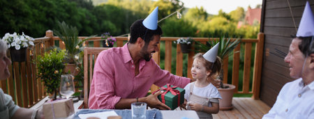 Multi generation family celebrating birthday and have garden party outside in the backyard on patio.の写真素材