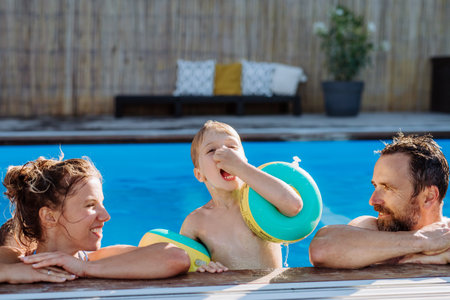 Happy young family spending summer time together in their pool.
