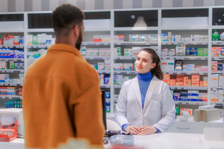Young pharmacist selling medications to the customer.の写真素材