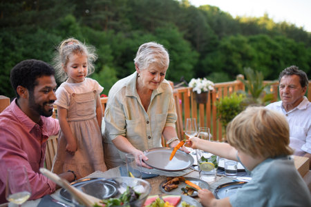Multigenerational family eating dinner at barbecue party.の写真素材