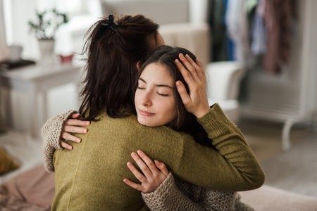 Teenage girl hugging her mother at home.の写真素材
