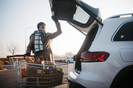 Senior man giving his purchase in electric car trunk.