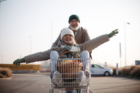 Senior couple going home from grocery store, having fun.の写真素材