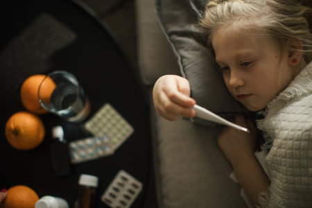Little sick girl measuring her body temperature.