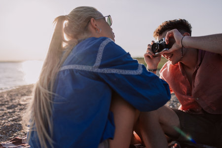 Young boy taking photo of his beautiful girlfriend at beach during sunset.の写真素材