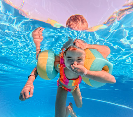 Little girl in swimsuit diving in swimming pool.の写真素材