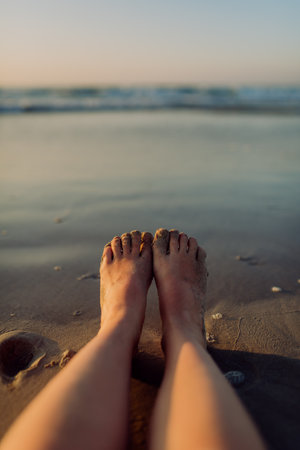 Close-up of woman with her feet on beach.の写真素材