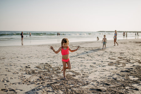 Little girl jumping in the sand on beach during summer holliday.の写真素材