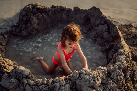 Little girl playing on the beach, digging hole in sand.の写真素材