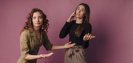 Studio shoot of two young women, one calling with mobile phone.の写真素材