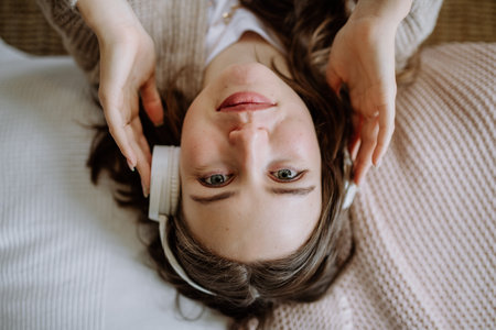 Top view of young woman listening music trough headphones.の写真素材