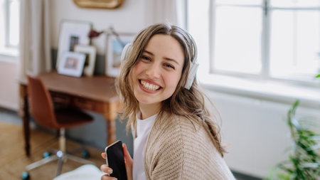 Young woman listening music trough headphones in her apartment.の写真素材