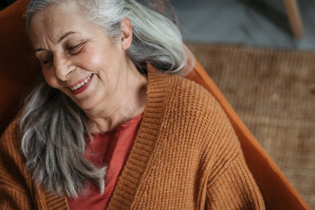 High angle view of happy senior woman sitting in a living room.の写真素材