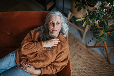 Portrait of pensive senior woman sitting in home.の写真素材