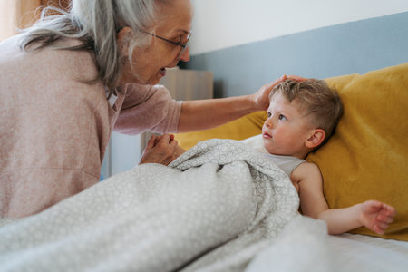Grandmother giving her grandson in the bed.の写真素材