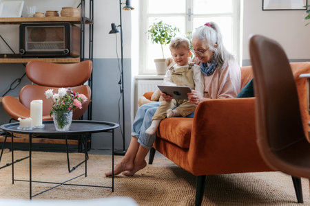 Grandmother looking fairytale with her grandson on digital tablet.の写真素材