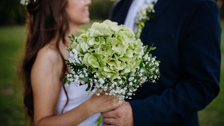 Close-up of bride and groom holding wedding bouquet, outdoor in the meadow.の写真素材