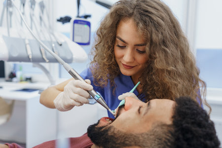 Young woman dentist doing preventive examination to multiracial man.