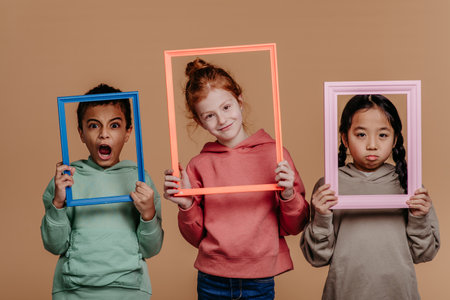 Portrait of three children with frames, studio shoot. Concept of diversity in friendship.の写真素材