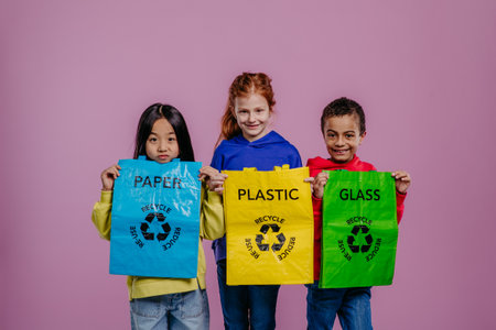 Portrait of three children posing with bins for separated waste.の写真素材