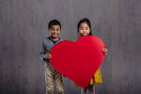 Studio shoot of little boy and girl holding model of heart.の写真素材