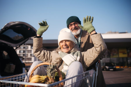 Senior couple going home from grocery store, having fun.の写真素材