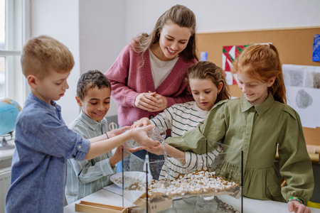 Young teacher making little greenhouse with their pupils, learning them about planting.の写真素材
