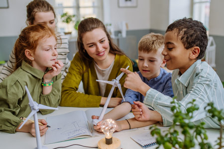 Young teacher with model of wind turbine learning pupils about wind energy.の写真素材