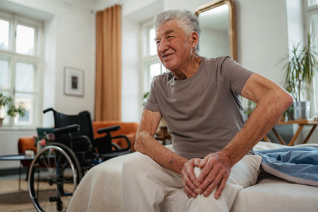 Portrait of senior man with knee pain sitting on a bed.の写真素材