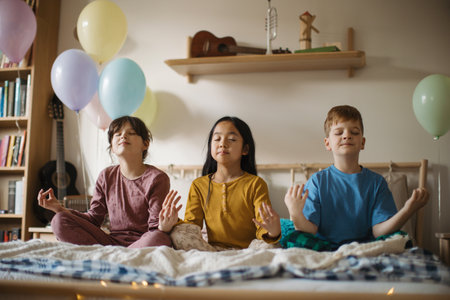 Three happy friends sitting on a bed and mediating.の写真素材