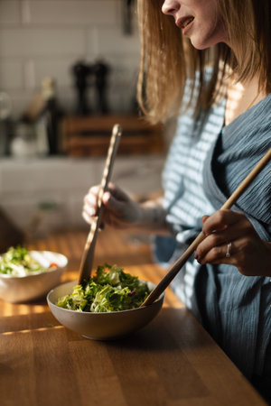 Young woman preparing salad in her kitchen.の写真素材
