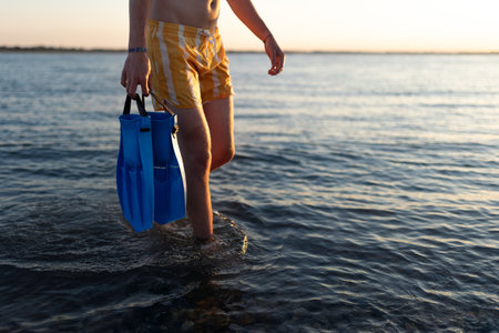Low section of boy in swimsuit with swimmers fins.の写真素材