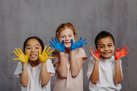 Portrait of happy kids with finger colours and painted hands.