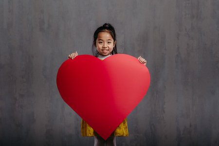 Little girl holding model of heart, studio photography.の写真素材
