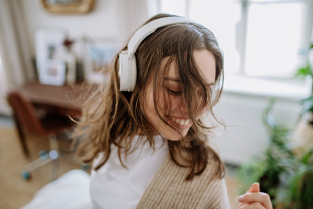 Young woman listening music trough headphones in her apartment.