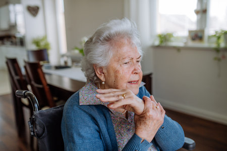 Portrait of senior woman on wheelchair with pain in her hand.の写真素材