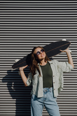 Portrait of young happy woman outdoor with skateboard. Youth culture and commuting concept.の写真素材