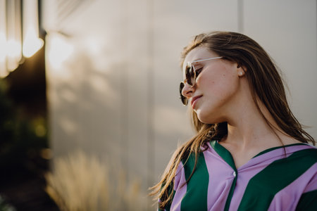 Portrait of beautiful young woman outdoor in city, during sunset.の写真素材