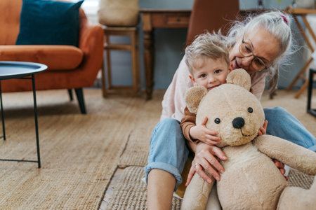 Grandmother cuddling her little grandson with bear toy.の写真素材