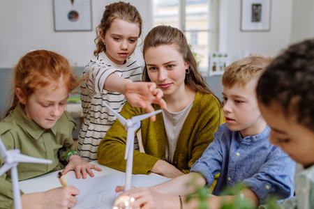 Young teacher with model of wind turbine learning pupils about wind energy.の写真素材