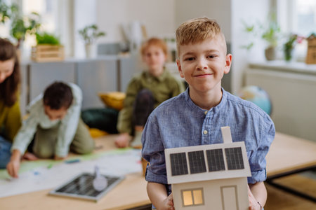 Little boy posing with model of house with solar system during a school lesson.の写真素材