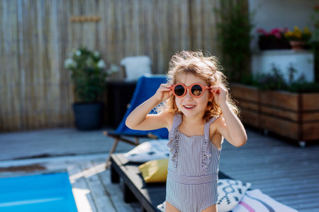 Portrait of little girl in swimsuit with sunglasses.