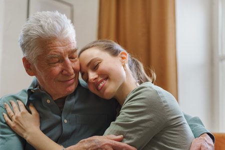Granddaughter hugging her grandfather in their home.