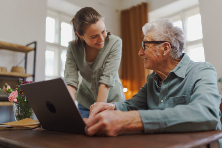 Granddaughter showing something to her grandfather on laptop.の写真素材